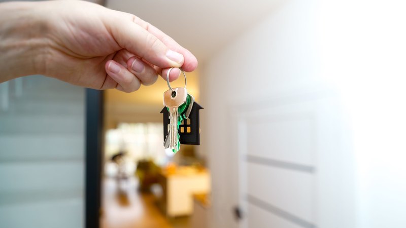 Hand holding apartment keys inside a modern home